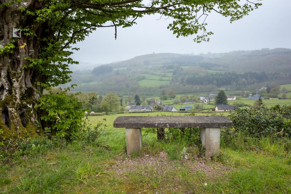un banc en pierre face à un paysage complétement bouché par la pluie